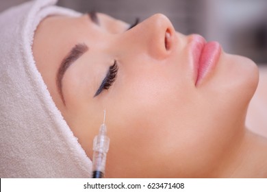 The doctor cosmetologist makes the Botulinotoxin injection procedure for tightening and smoothing wrinkles on the face skin of a beautiful, young woman in a beauty salon.Cosmetology skin care. - Shutterstock ID 623471408