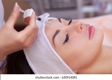 The doctor cosmetologist makes the Botulinotoxin injection procedure for tightening and smoothing wrinkles on the face skin of a beautiful, young woman in a beauty salon.Cosmetology skin care. - Shutterstock ID 630914081