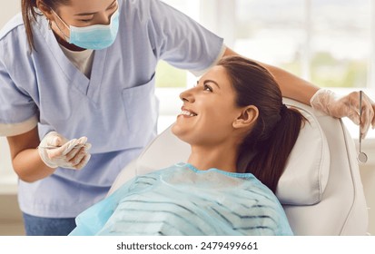 Doctor dentist, nurse, or orthodontist conducting a dental examination for a smiling patient in the hospital office. Focused on providing oral care and ensuring dental health in the dentistry clinic. - Powered by Shutterstock