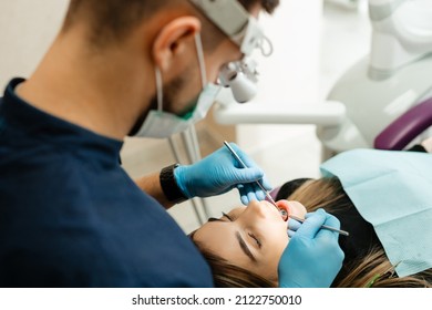 Doctor Dentist Treats The Teeth Of A Patient Under A Microscope