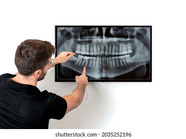 Doctor of Dentistry pointing at the monitor, reviews panoramic x-ray of a denture - Powered by Shutterstock