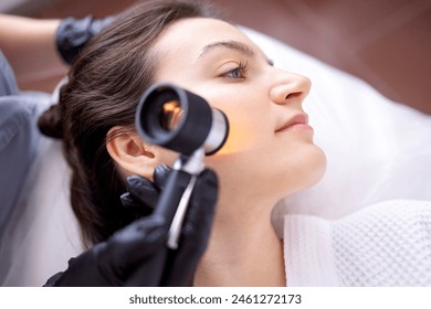 Doctor dermatologist examines skin of client face of beauty salon with a dermatological lens. Dermatoscopy. Free space for text. - Powered by Shutterstock