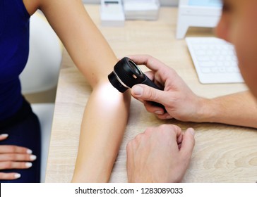 Doctor dermatologist examines the skin of the girl's patient for the presence of moles, birthmarks, tumors. Dermatoscopy, prevention of melanoma, skin cancer, Dermatoscope.