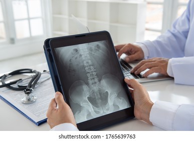 doctor diagnose pelvis hipbone sacrum coccyx spine x-ray image on digital tablet screen with radiologist  team.