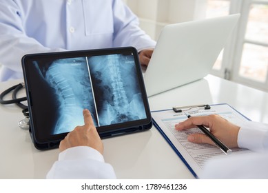 Врач диагностирует рентгеновское изображение позвонков позвоночника на цифровом планшете для диагностики грыжи межпозвоночного диска с помощью команды радиологических технологов.