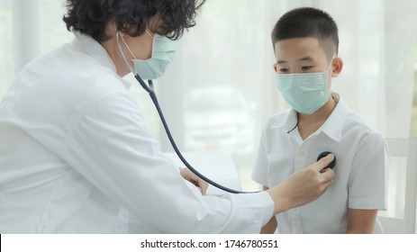 The Doctor Diagnosing Disease For Kid Patient And Wearing Surgical Mask For Health Care From Coronavirus (COVID-19). Health Care And Prevent From Risk Of Coronavirus (COVID-19) Concept.