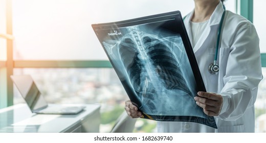 Doctor diagnosing patient’s health on asthma, lung disease, COVID-19, coronavirus or bone cancer illness with radiological chest x-ray film for medical healthcare hospital service - Shutterstock ID 1682639740