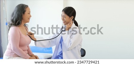 Doctor diagnosing senior female patient with stethoscope. Senior woman visits doctor for examination at hospital examination room.
