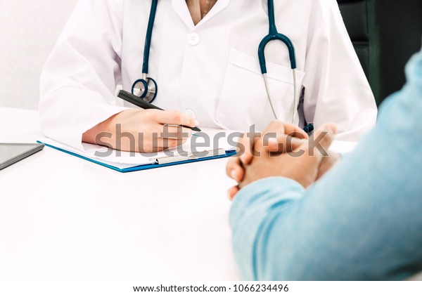 Doctor discussing and\
consulting with male patien on doctors table in hospital.healthcare\
and medicine