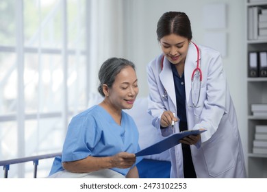 Doctor discussing medical report with elderly patient in hospital. Healthcare professional providing information to senior woman in hospital bed. - Powered by Shutterstock