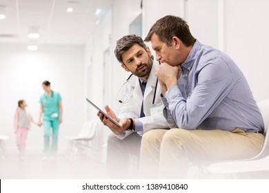 Ärztin, die über die digitale Tablette mit reife Patientin im Krankenhaus diskutiert