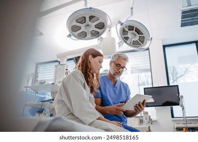 Doctor discussing test resulst with teenage patient, showing data on tablet in emergency room. - Powered by Shutterstock