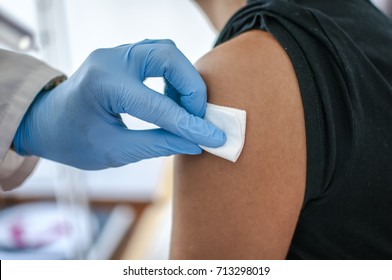 Doctor disinfects skin of patient before vaccination