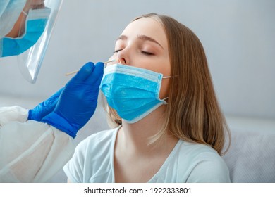 Doctor Do PCR Test To Woman Patient. Nurse Take Saliva Sample Through Nose With Cotton Swab To Check Coronavirus Covid 19. Medical Worker Wearing Protective Mask Do PCR Test At Home Or In Clinic.