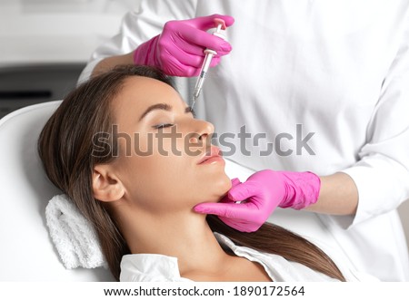 The doctor does injections to correct the hump on the nose with the beauty of the blonde. The beautician doees injections against wrinkles on the face. Women's cosmetology in a beauty salon.
