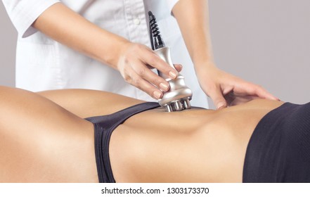 The doctor does the Rf lifting procedure on the stomach and hips of a woman in a beauty parlor. Treatment of overweight and flabby skin.