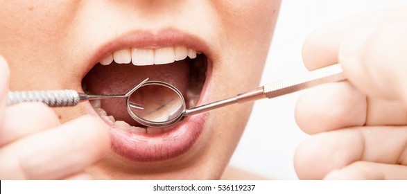 Doctor doing dental treatment to his patient in clinic. Teeth inspection and repair concept