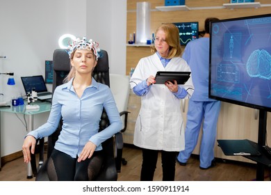 Doctor Doing A Girl's Brain Scan Procedure In A Scientific Lab. Brain Waves Scanning Helmet