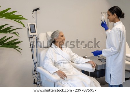 Doctor doing IV infusion for senior woman patient in beauty clinic.