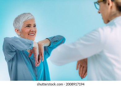 Doctor Doing Medical Exam With Senior Woman, Checking For Carpal Tunnel Syndrome.