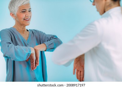 Doctor Doing Medical Exam With Senior Woman, Checking For Carpal Tunnel Syndrome.