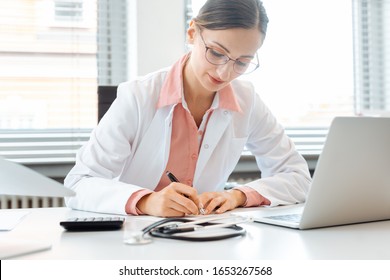 Doctor Doing Office Works And Administration On The Desk In Her Office Writing