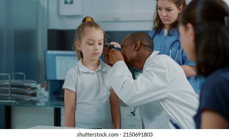 Doctor doing otology examination with otoscope to see ear infection in medical cabinet. Specialist using otoscopy tool on small kid at consultation appointment to find disease diagnosis. - Powered by Shutterstock