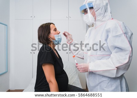 A doctor doing a PCR to detect Covid 19 on a pregnant woman in the doctor's office to avoid the risk of contagion.