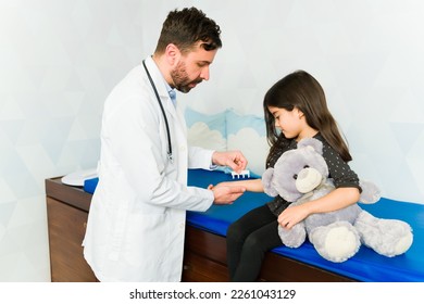 Doctor doing a prick test or SPT testing for allergies on the skin arm of an adorable little girl with a teddy bear - Powered by Shutterstock