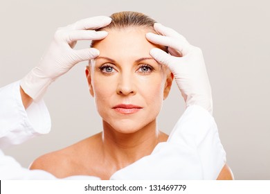 Doctor Doing Skin Check On Middle Aged Woman Before Cosmetic Surgery