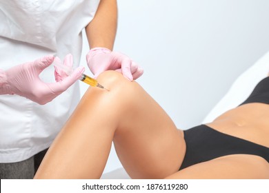Doctor doing stem cell therapy on a patient's knee after the injury. Treating knee pain with platelet-rich plasma injection. Treatment of arthritis and osteoarthritis.Medical and cosmetology concept.