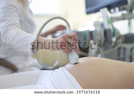 Doctor doing ultrasound examination of pregnant woman patient in clinic closeup