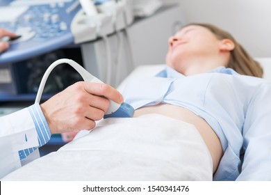 Doctor doing ultrasound screening checkup in clinic office. Clinical diagnostics and professional consultation. Doctor ultrasound examine female patient abdomen at hospital. Prenatal diagnosis center