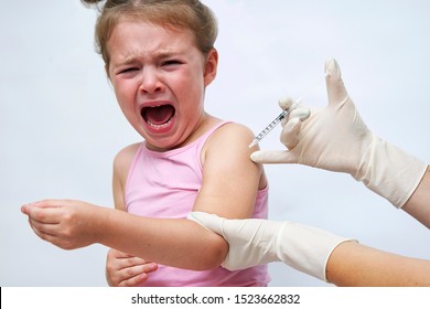 Doctor doing vaccine injection to crying girl on a white background