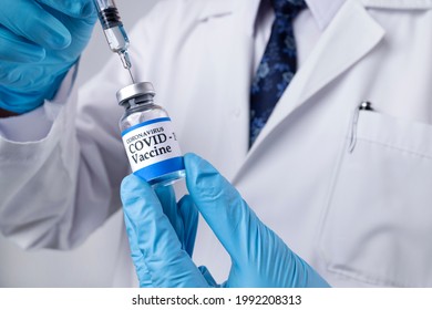 A Doctor Drawing Liquid From A Glass Vial Labelled Covid-19 Vaccine. Booster Vaccine.