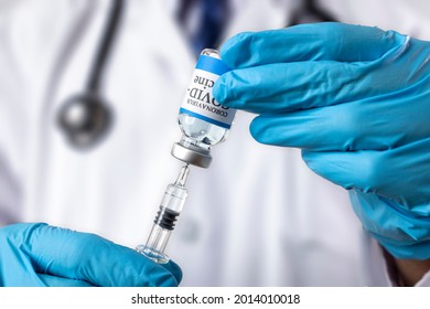 A Doctor Drawing Liquid From A Glass Vial Labelled Covid-19 Vaccine. Vaccine Booster Concept.