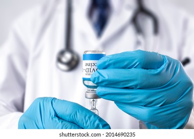 A Doctor Drawing Liquid From A Glass Vial Labelled Covid-19 Vaccine.  Booster Vaccination.