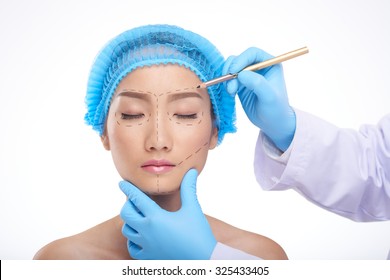 Doctor Drawing Perforation Lines On Face Of Patient Before Surgery