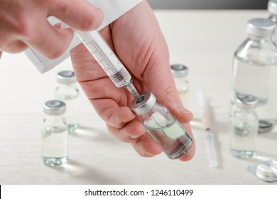 Doctor drawing vaccine into a syringe from a vial. Seasonal infectious diseases prevention and control. - Shutterstock ID 1246110499