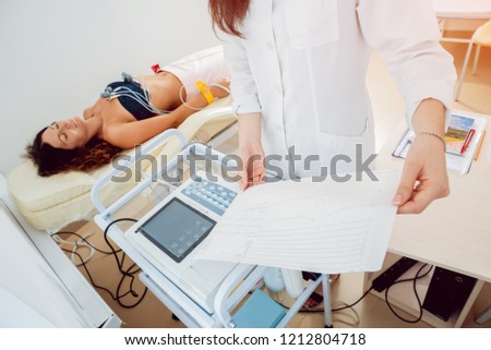 Doctor with electrocardiogram equipment making cardiogram test to patient in clinic. Diagnostic, healthcare, medical service