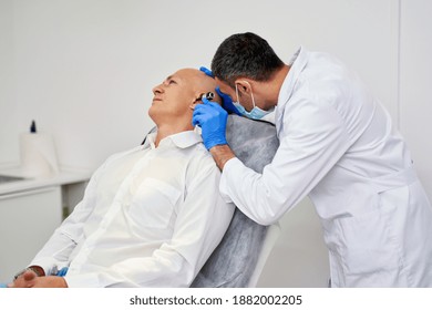 Doctor ENT Checking Ear With Otoscope To Man Patient At Hospital. High Quality Photo