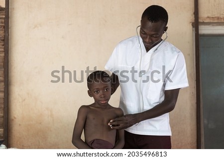 Doctor examinating the chest sounds of a small black boy with a sad expression on his face; Covid-19 screening concept