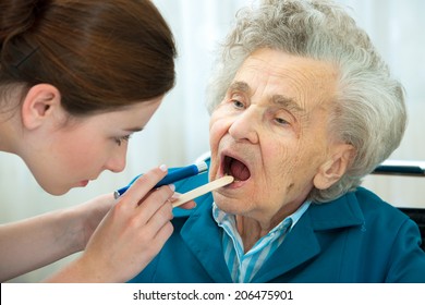 Doctor Examines Elderly Woman For Sore Throat