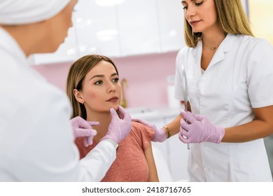 A doctor examines the patient before the aesthetic procedures. The patient looks at herself and tells her what she wants to change. - Powered by Shutterstock