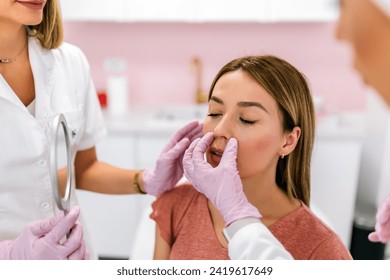 A doctor examines the patient before the aesthetic procedures. The patient looks at herself and tells her what she wants to change. - Powered by Shutterstock