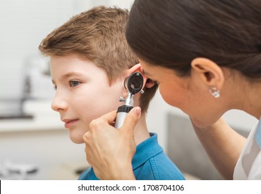 Doctor Examining Boy Ear , Using Otoscope, In Doctors Office. Child Receiving A Hearing Test