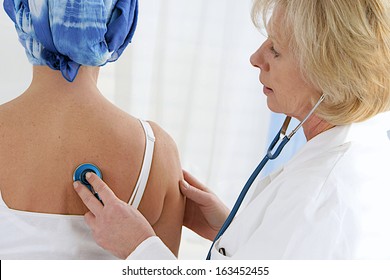 Doctor Examining  Cancer Patient In A Head Scarf  With Stethoscope 