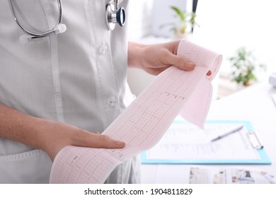 Doctor examining cardiogram in medical clinic, closeup