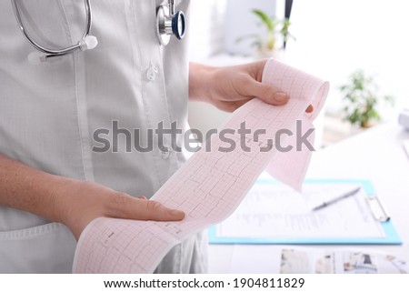 Doctor examining cardiogram in medical clinic, closeup
