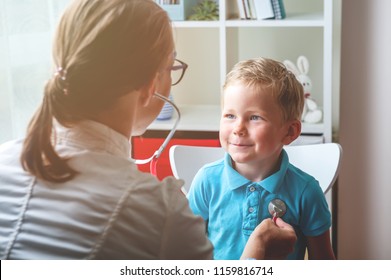 Doctor examining child by stethoscope. Happy child boy at the doctor's consultation in hospital. Medical exam at clinic by pediatrician. Pediatric,  healthcare and people concept.